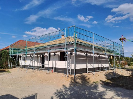 Eingeschossiger Bungalow von ZET Massivhaus während der Rohbauphase mit Baugerüst und teilweise eingedecktem Dach.