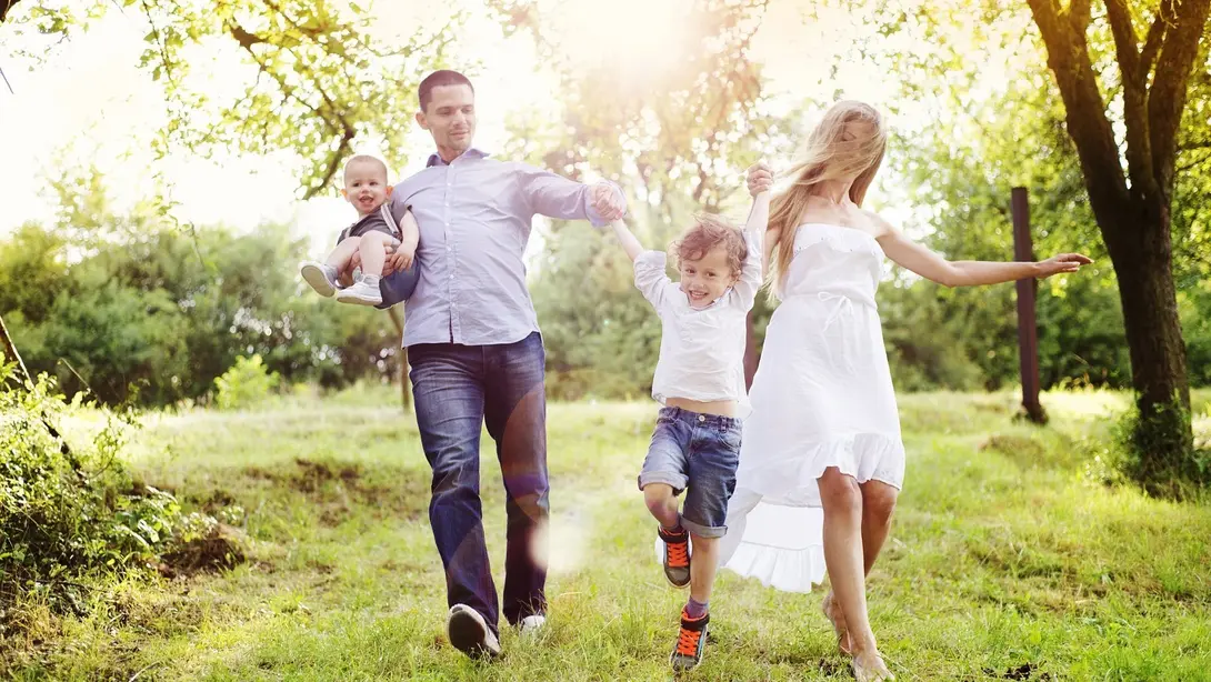 Familie mit zwei Kindern genießt gemeinsame Zeit in einer grünen Parklandschaft