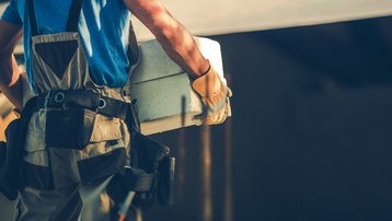 Handwerker trägt Pflasterstein zur Gestaltung einer Grundstückszufahrt
