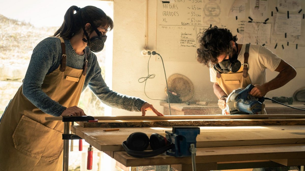 Zwei Personen arbeiten mit Schutzmasken an Holzarbeiten für den Innenausbau
