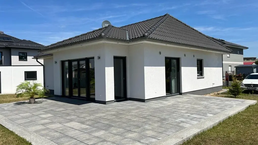 Moderner weißer Bungalow mit Walmdach und großer Terrasse