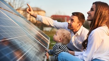 Familie betrachtet Photovoltaikmodule auf einem bestehenden Dach