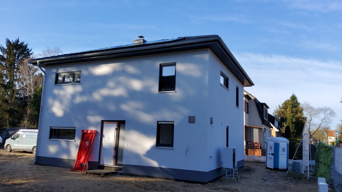 Modernes zweigeschossiges Massivhaus im Bau mit heller Fassade und Walmdach