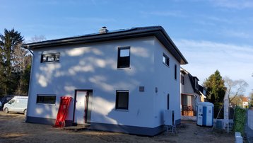 Modernes Massivhaus im Bau – Außenansicht Modernes zweigeschossiges Massivhaus im Bau mit heller Fassade und Walmdach