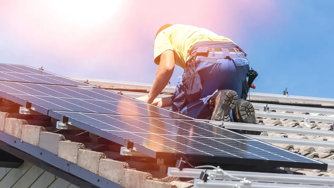 Photovoltaik-Installation auf dem Hausdach Monteur installiert Photovoltaikmodule auf einem Hausdach bei sonnigem Wetter