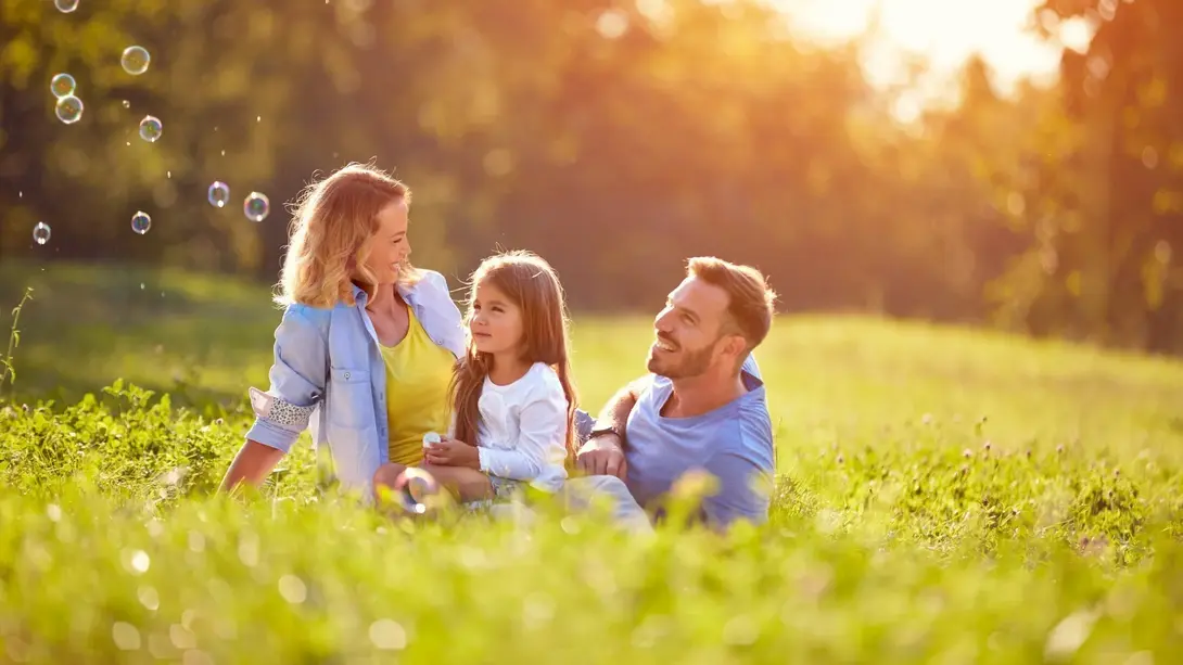 Familienzeit im Grünen Familie sitzt entspannt auf einer sonnigen Wiese und genießt gemeinsame Zeit im Grünen.