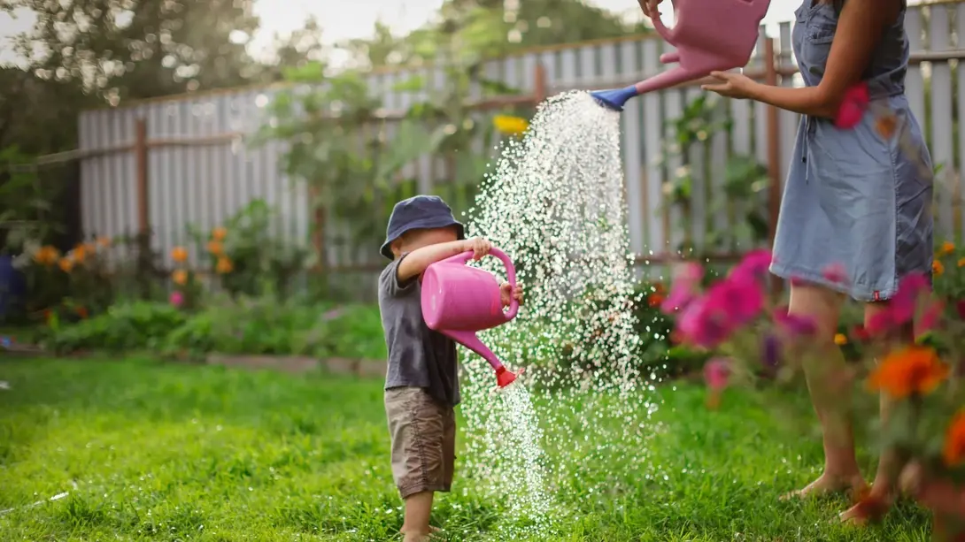 Gemeinsame Gartenzeit mit der Familie Mutter und Kind gießen gemeinsam Blumen im Garten