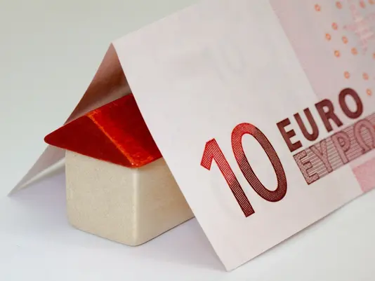 Kleines Hausmodell neben einem gefalteten Zehn-Euro-Schein