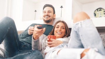 Paar entspannt gemeinsam im offenen Wohnbereich eines hellen Hauses