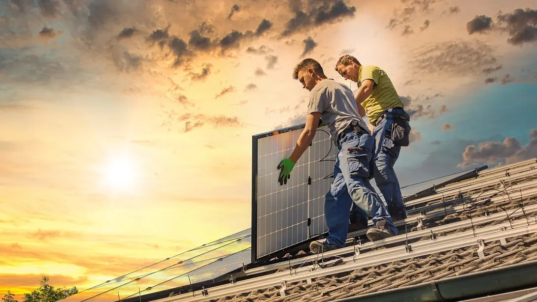 Photovoltaikanlage auf dem Hausdach installieren Zwei Handwerker installieren eine Photovoltaikanlage auf einem Hausdach