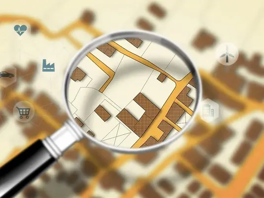 Passendes Baugrundstück finden Lupe vergrößert ein Grundstück auf einem digitalen Stadtplan